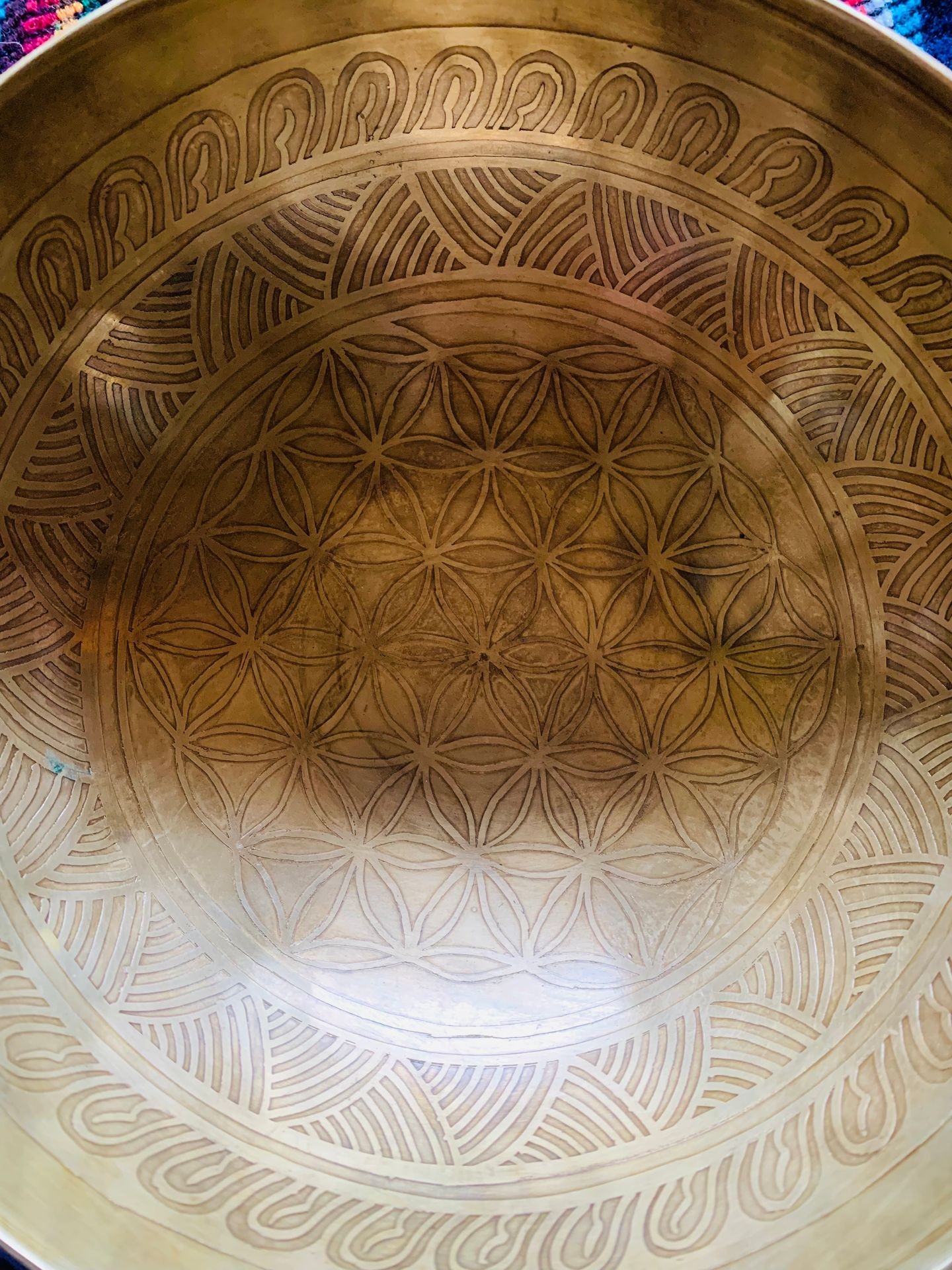 Close-up of a brass bowl with intricate etched geometric patterns on the interior surface.